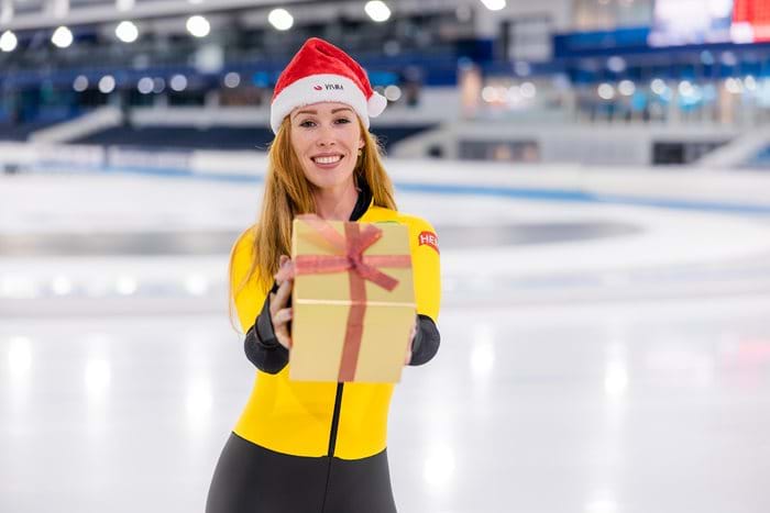 Woman with santa hat on ice, holding present